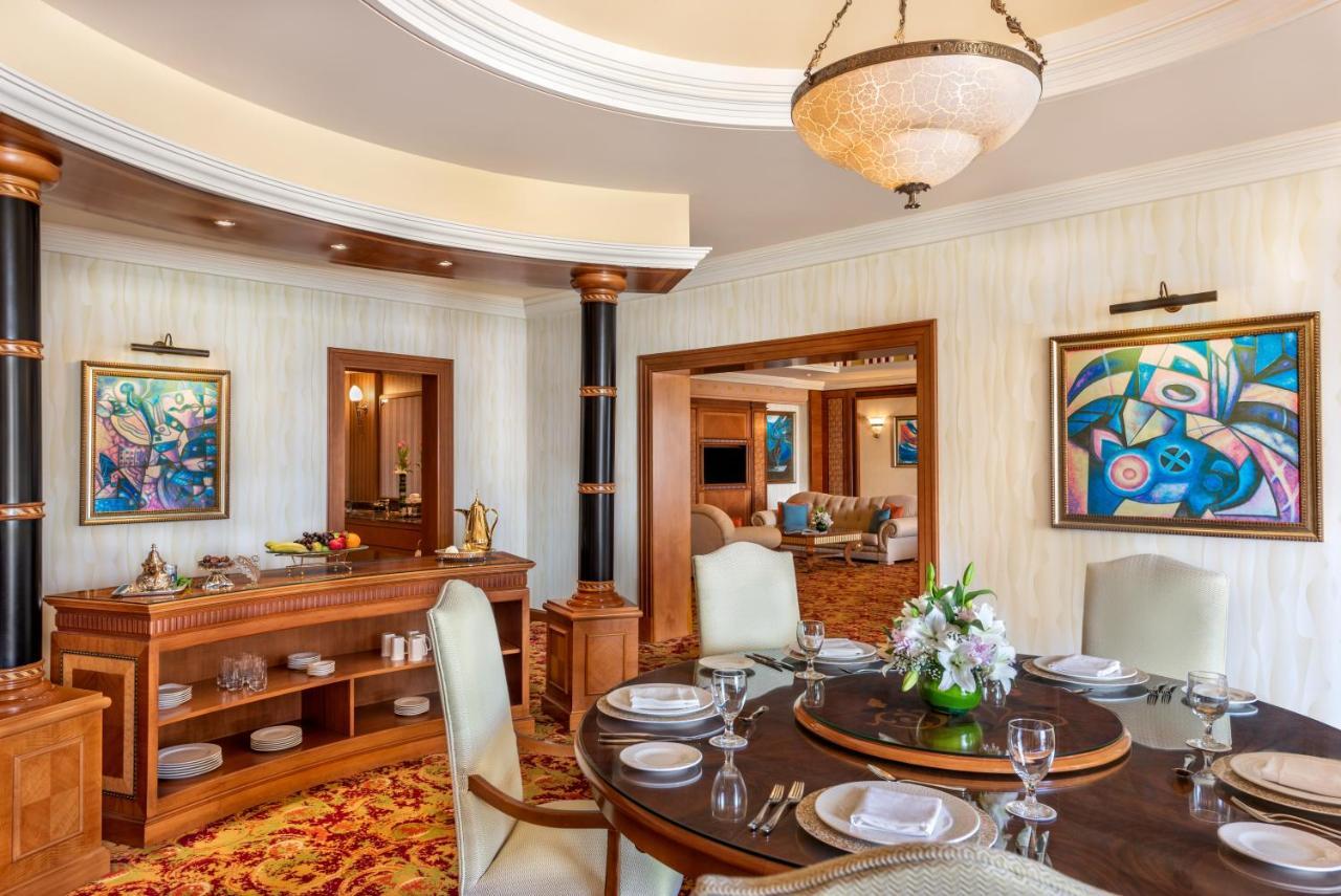 Al Raha Beach Resort & Spa Abu Dhabi Ngoại thất bức ảnh The photo shows an elegantly designed dining area and a glimpse into a luxurious living space. 

In the foreground, a round dining table is set with fine china, glassware, and a centerpiece featuring fresh flowers. The chairs surrounding the table ha