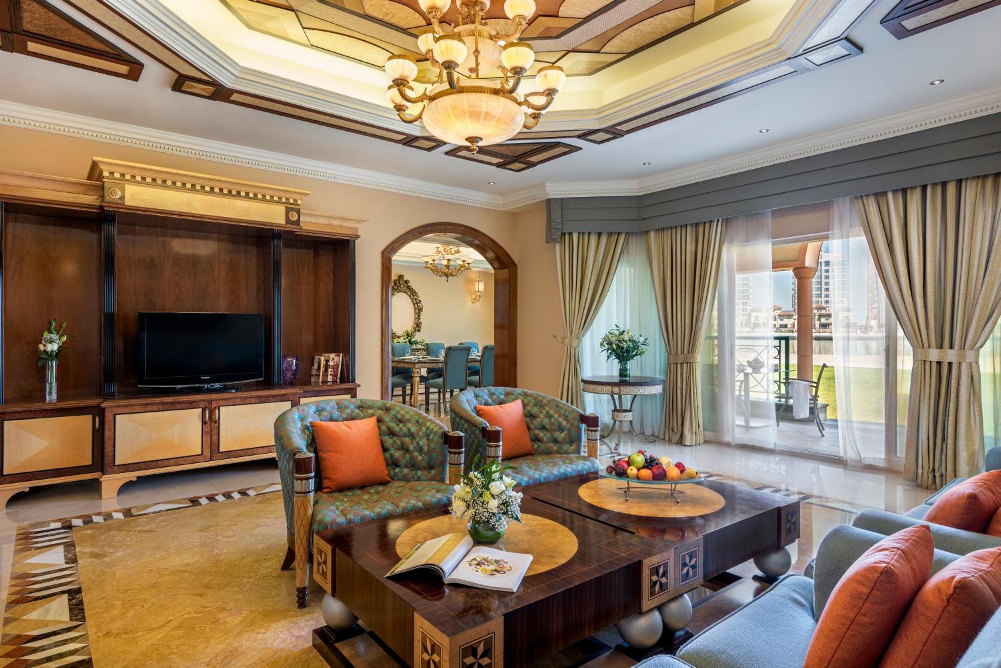 Al Raha Beach Resort & Spa Abu Dhabi Ngoại thất bức ảnh The photo depicts a luxurious living room with elegant decor. It features two green upholstered sofas accented with orange pillows, arranged around a stylish coffee table. The coffee table showcases decorative items, including a magazine and a bowl o